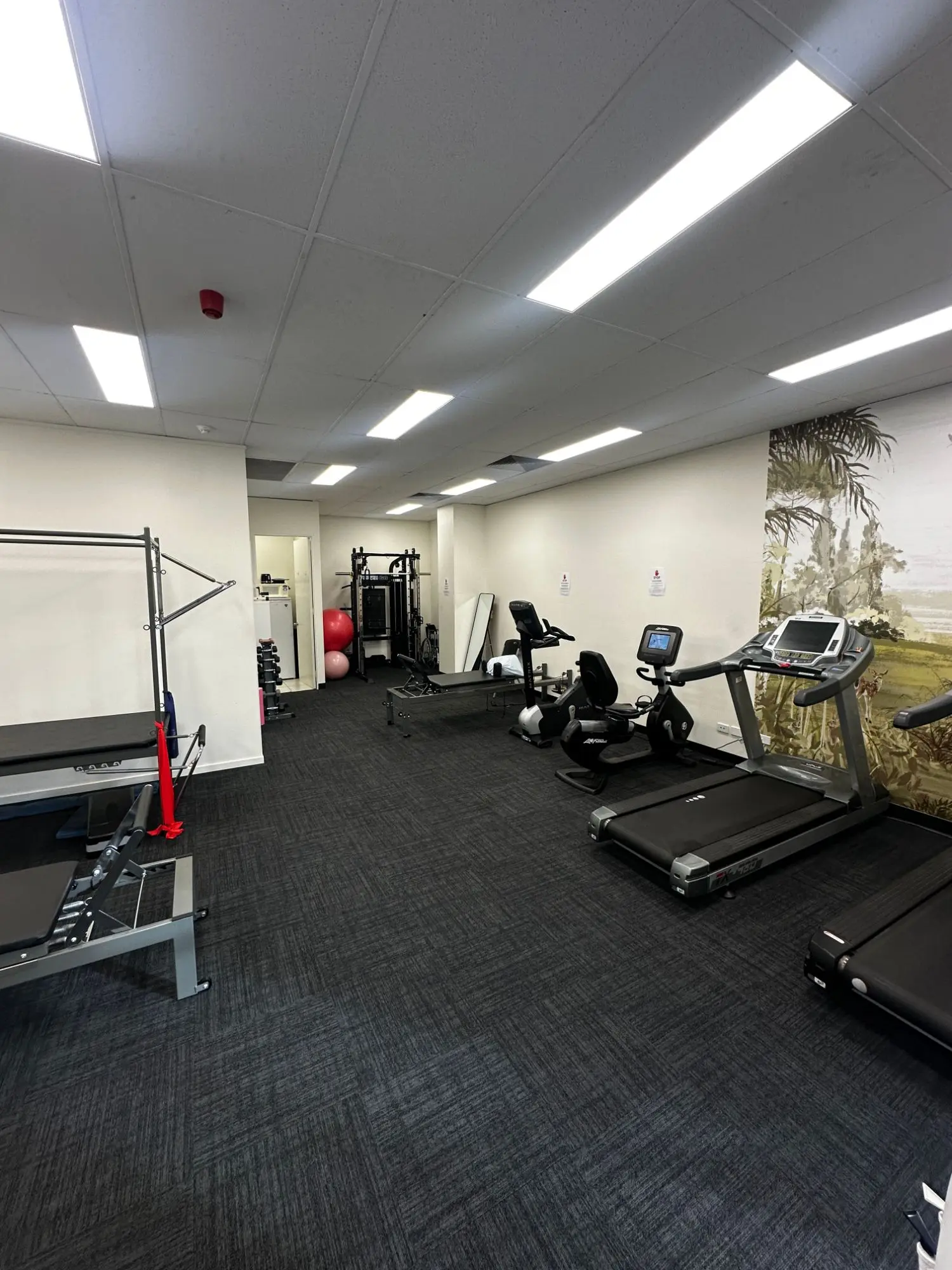 The pulmonary rehabilitation exercise room with treadmills, bikes, strength rack and reformer